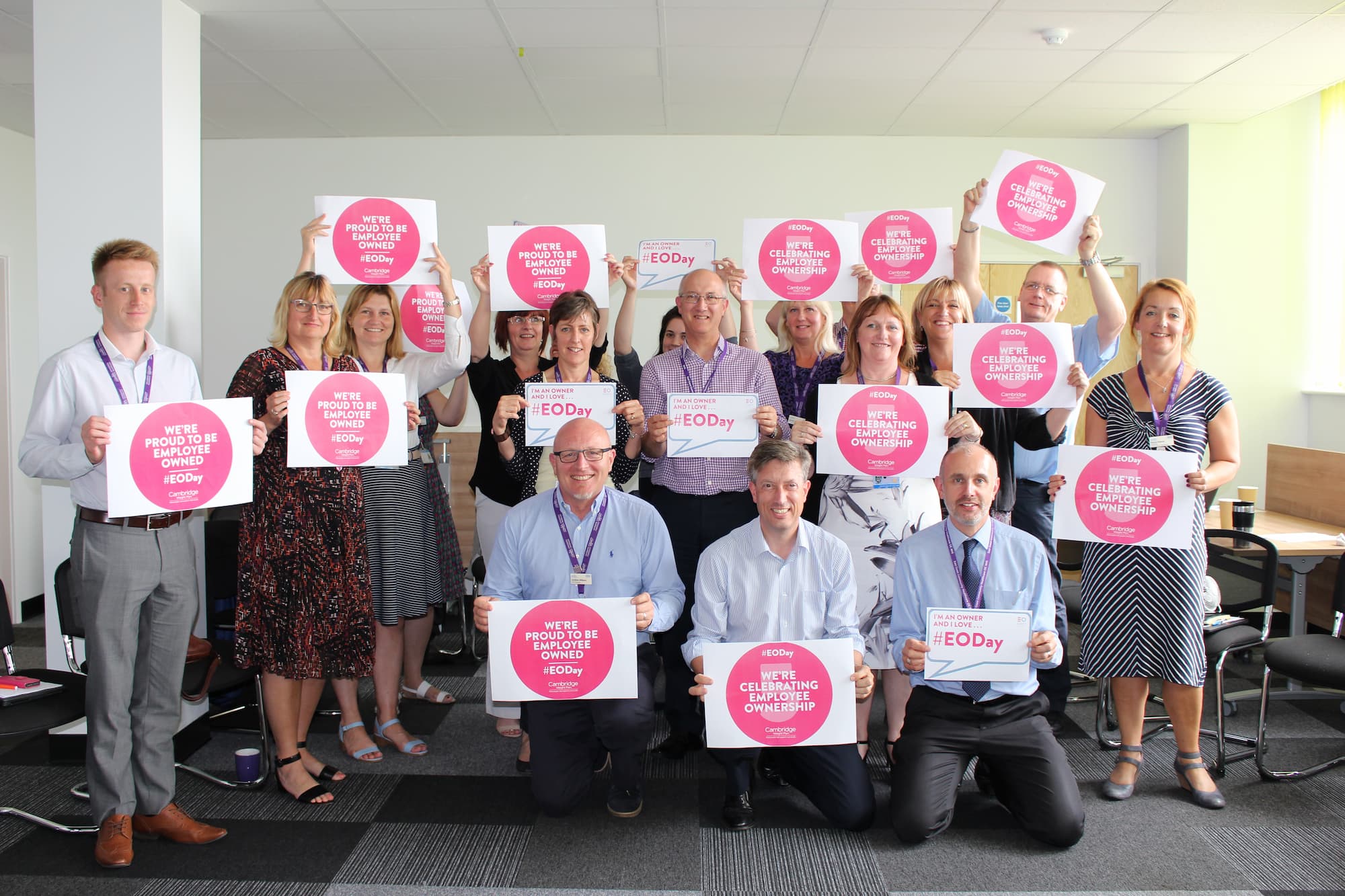 a selection of staff holding employee ownship posters