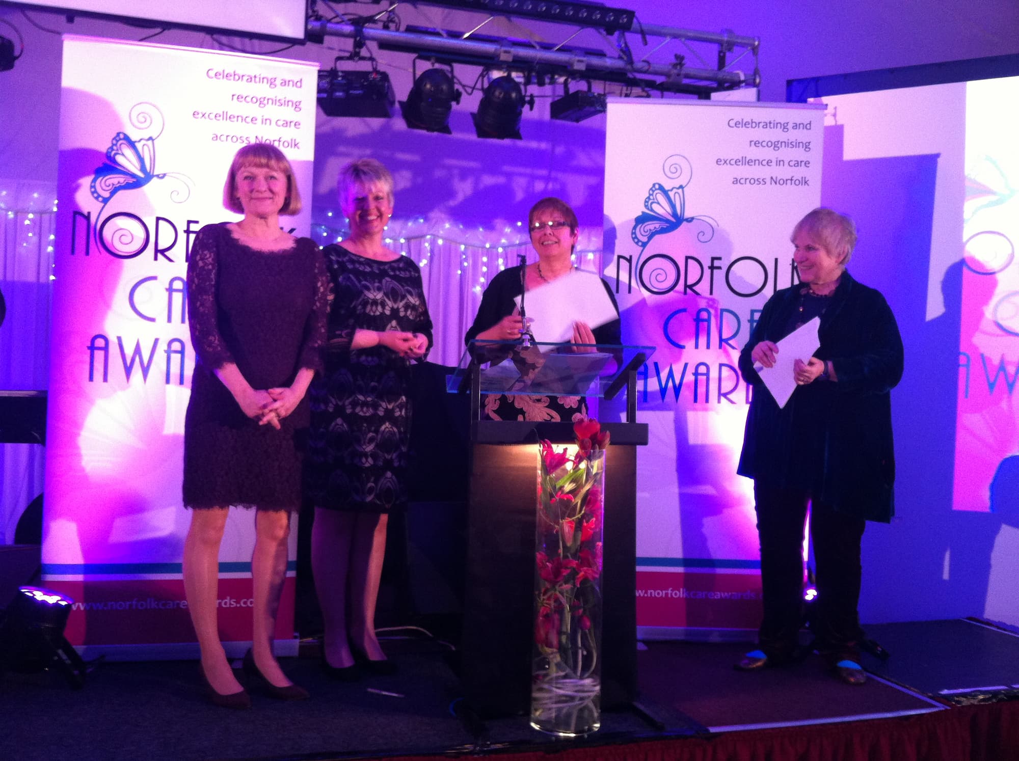 ECCH’s Macmillan Community Cancer Matrons standing on a stage recieving the Norfolk Care Award for Excellent People Centred Care and Support.