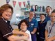 A nurse giving another nurse the flu jab with other staff members qued up
