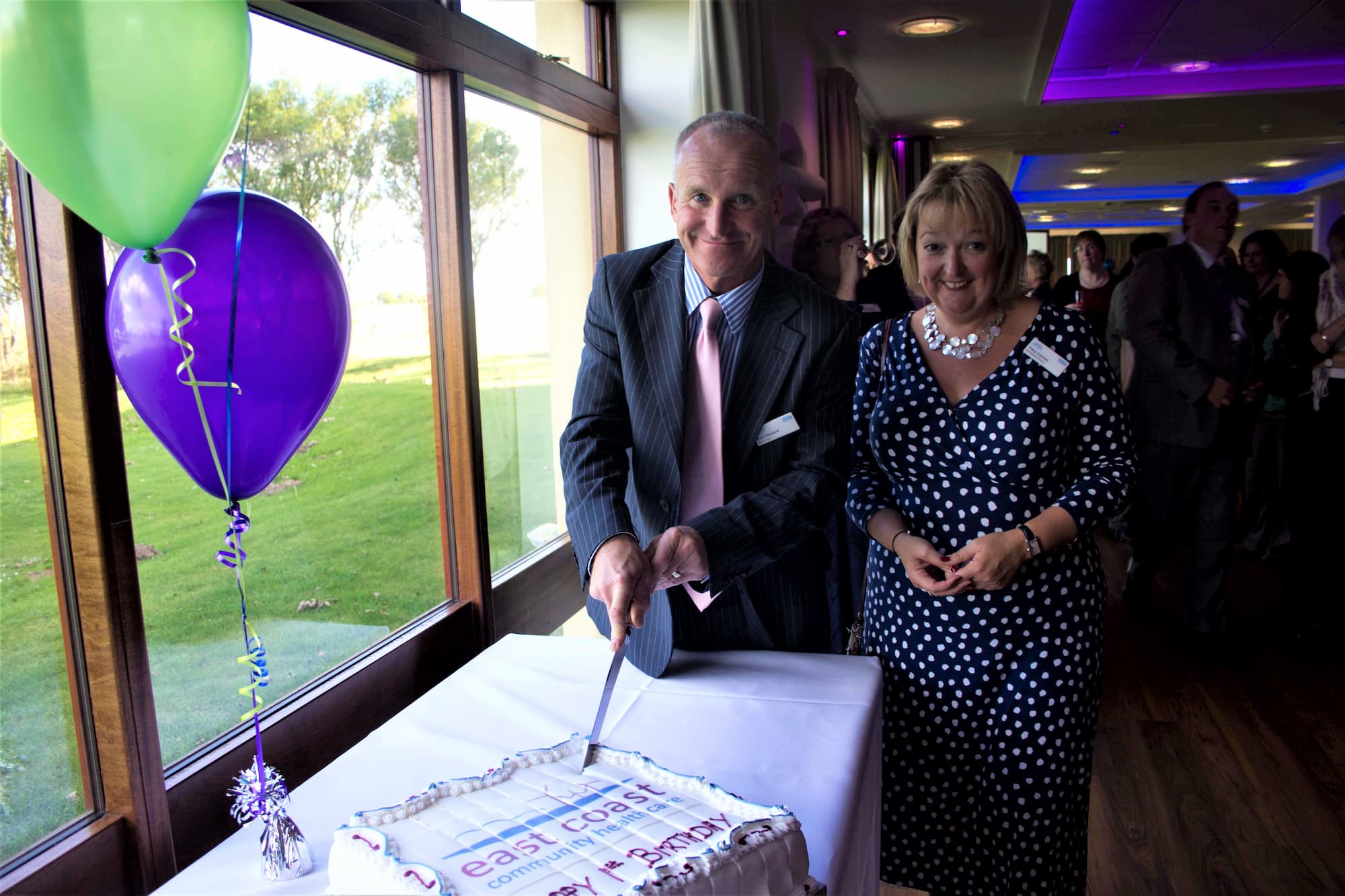 Paul Stewart, Chair and Tracey Cannel, CEO cutting a birthday cake celebrating ECCH's 1st birthday
