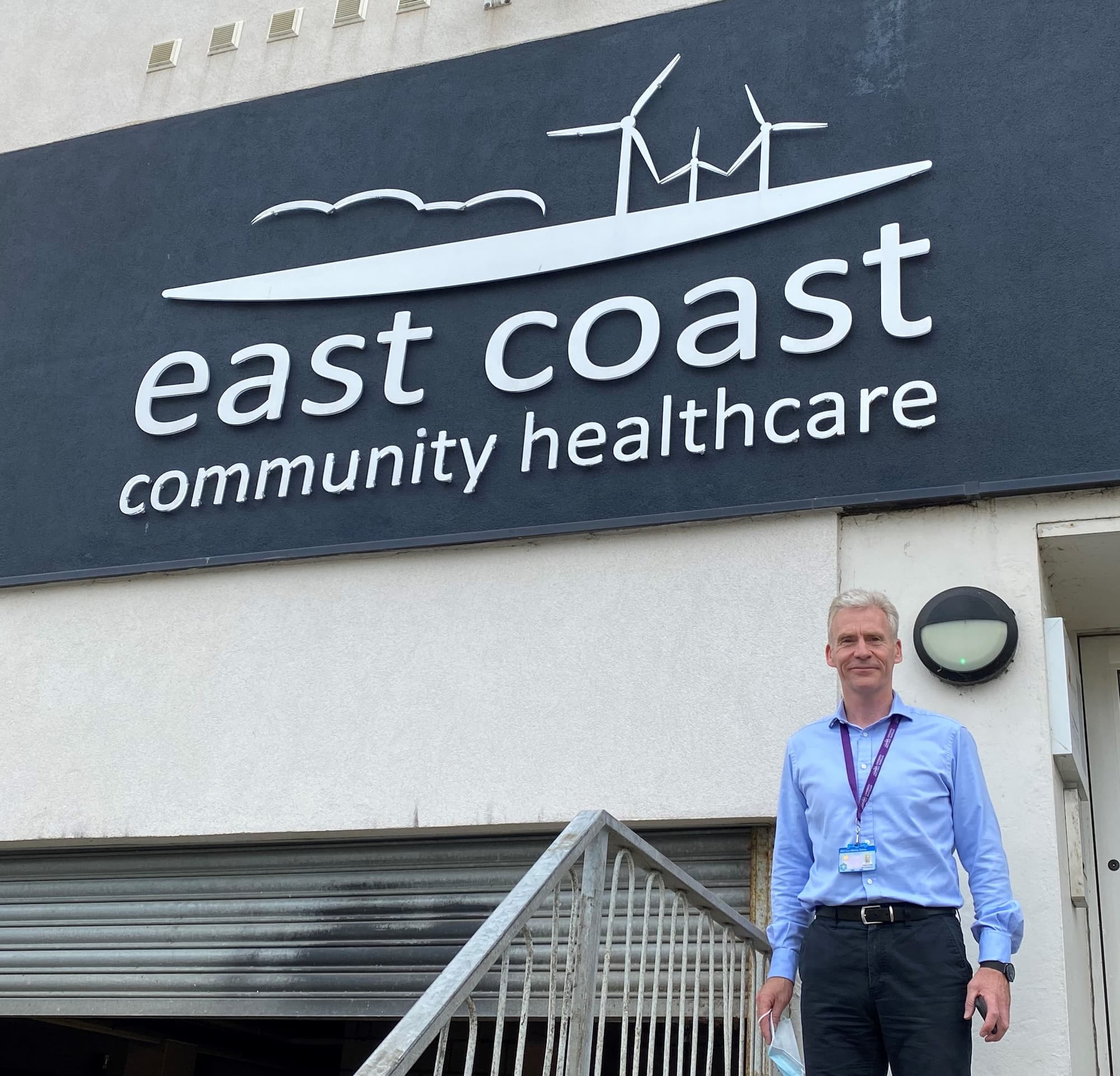 ECCH CEO Ian Hutchison standing outside Hamilton House side entrance with ECCH logo in background